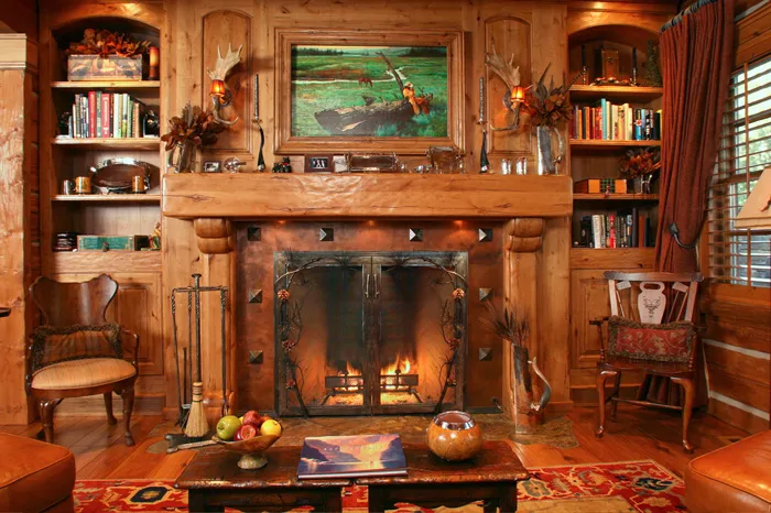 Rustic great-room library with custom built-in bookcases and a hand-carved fireplace mantel by The Joinery