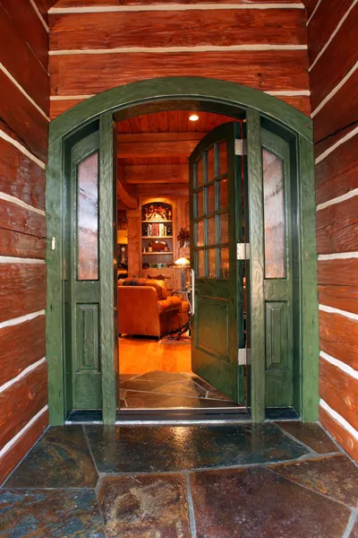 Custom arched entry door opening into a warm timber interior