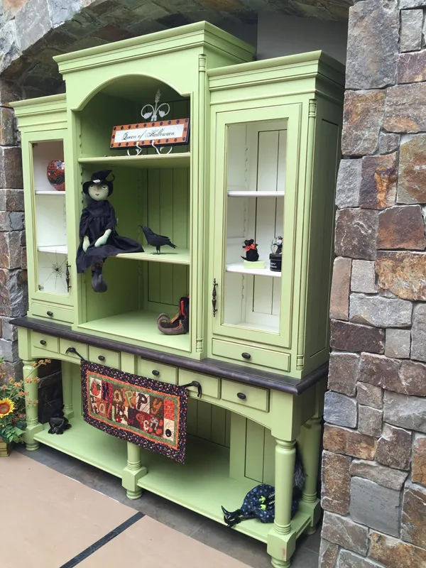 Custom green-painted display hutch against a stone wall