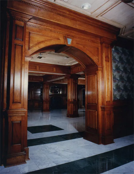 Grand wood-paneled foyer with an arched passage and checkerboard floor