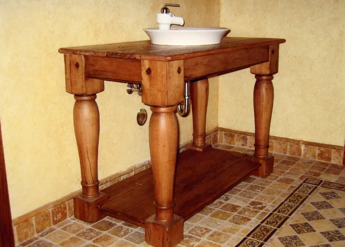 Hand-built pine vanity table with a vessel sink on a tiled floor