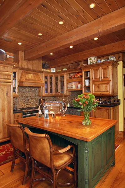 Custom kitchen with a sage-green island, raised-panel cabinets, and stone accents