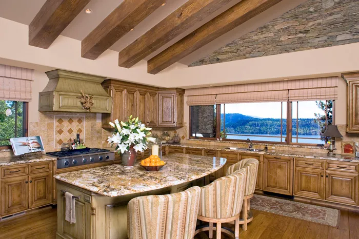 Tuscan-style kitchen with a granite island, beamed ceiling, and lake views